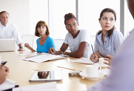People sitting around a meeting table and looking towards the speaker.