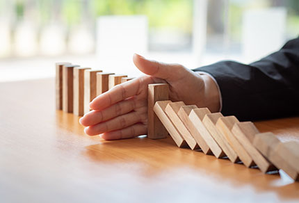 A hand preventing domino blocks from falling.