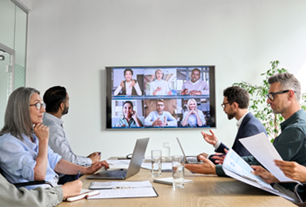 Employees gathered in a meeting room having an online conference video call.