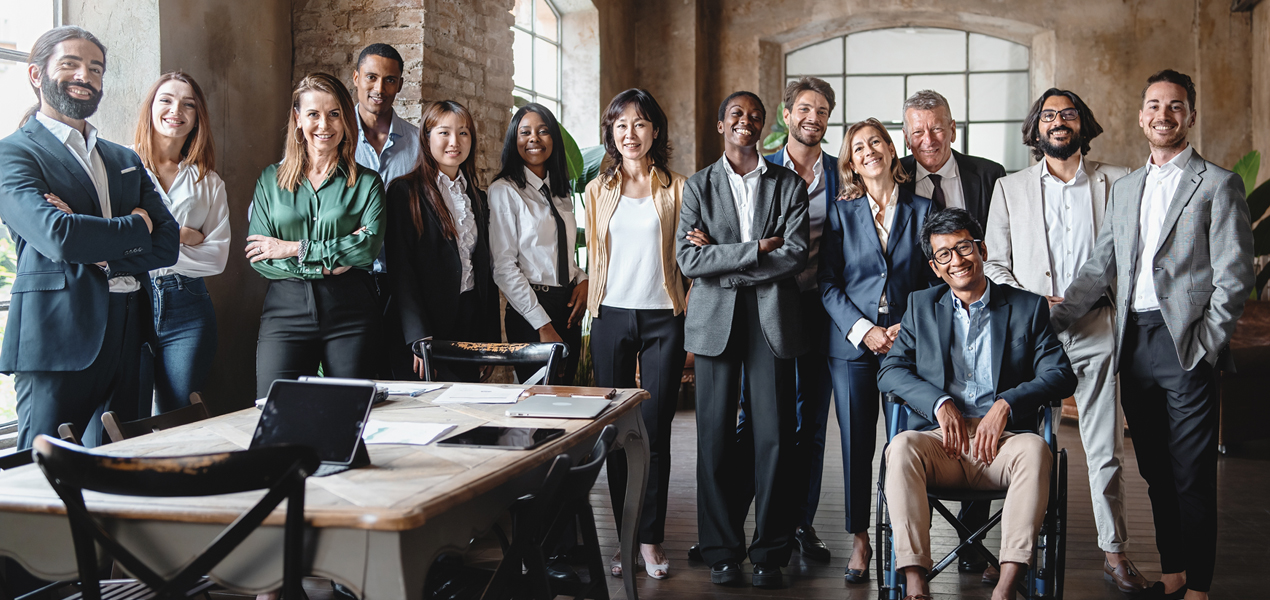 A diverse team of different ages, race, genders, and mixed-ability facing the camera.